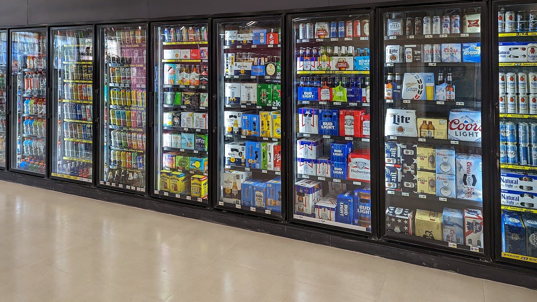 A long wall of glass-door coolers stocked with beer, seltzers and cold drinks